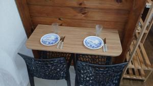 a wooden table with two chairs and plates on it at Suíte 77 privativa , há 11km da vila germânica in Blumenau