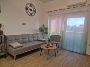 a living room with a couch and a table and a clock at Apartman Meghan in Pula