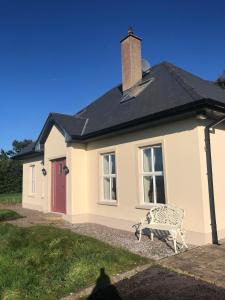 a white house with a bench in front of it at Ashmount Lodge in Ballynageragh