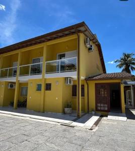 a yellow building with a palm tree in front of it at Ipê Suites Juquehy in Juquei