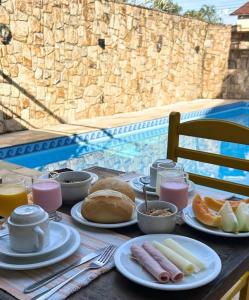 a table with plates of food on a table near a pool at Ipê Suites Juquehy in Juquei
