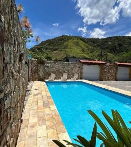 a swimming pool with chairs next to a building at Ipê Suites Juquehy in Juquei