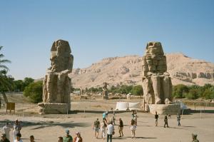 a group of people standing in front of two large stone statues at Sun wing guest house in Luxor