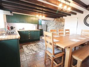 a kitchen with green cabinets and a wooden table at Cae Adar Farm in Wrexham