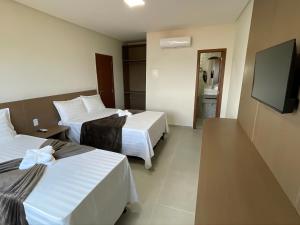 a hotel room with two beds and a flat screen tv at Sun Route Hotel in Cabo de Santo Agostinho