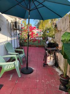 a patio with a blue umbrella and chairs and a grill at Nice private room with separate entrance in Port Richey