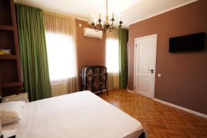 a bedroom with a white bed and a chandelier at Hotel Maisis Ezo in Kutaisi