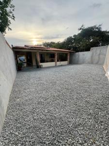 a house with a wall and a gravel driveway at Brisa das dunas in Tutóia