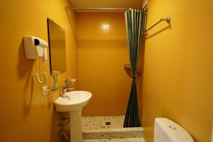 a yellow bathroom with a sink and a shower at Hotel Maisis Ezo in Kutaisi