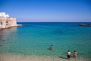 three people standing in the water at the beach at B&B Portorosso in Monopoli