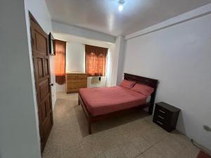 a bedroom with a bed with a red bedspread and a window at Hotel luque in Guayaquil
