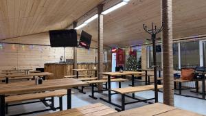 a dining room with wooden tables and a flat screen tv at Arrow Burabay in Borovoye
