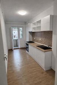 a kitchen with white cabinets and a wooden floor at Ultracentral Modern Apartment Toma Caragiu, Ploiesti in Ploieşti