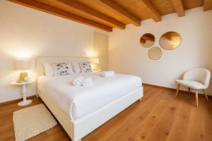 a bedroom with a white bed and a chair at Aurisina heart apartment in Aurisina