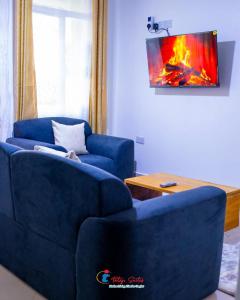 a living room with two blue couches and a fireplace at Tataji Suites in Kisii