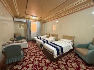 a room with four beds and chairs in it at دار اليقين in Medina