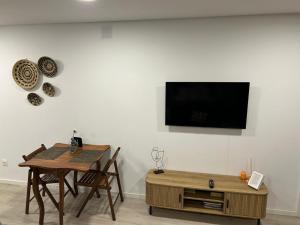 a dining room with a table and a tv on a wall at Casa da Zéfinha - STUDIO in Cinfães