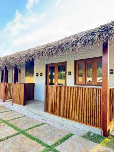 a house with a thatched roof and a wooden fence at POUSADA AMORIM in Santo Amaro