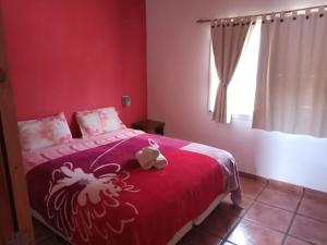 a bedroom with a bed with a red blanket with a rooster on it at Cabañas Dolce Far Niente in Tandil +25 photos