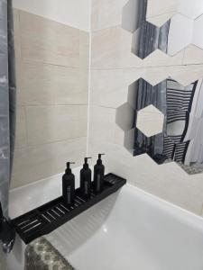 ein Badezimmer mit drei Flaschen auf einem Regal in der Badewanne in der Unterkunft Spacious - 8ight Havens in Folkestone + 160 Fotos