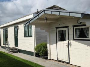 a small white house with a porch and a door at Chalet Zon & Zee in Zonnemaire