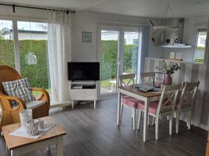 a living room with a dining table and a television at Chalet Zon & Zee in Zonnemaire