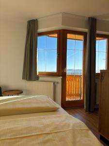a bedroom with a bed and a view of a balcony at Landhotel Bärnriegel in Mauth