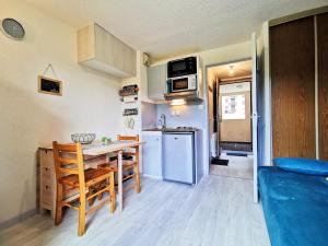 a small kitchen and dining room with a table and a refrigerator at Studio Lélex - classé meublé de tourisme 2 étoiles - pied des pistes - vue montagne in Lélex