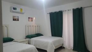 a bedroom with two beds and green curtains at Hotel Dieux Internacional in Pedernales
