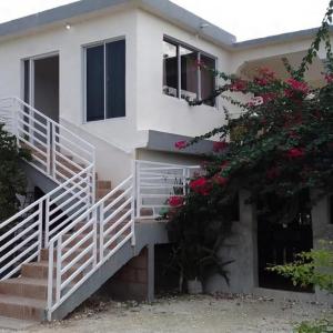 a white house with stairs and flowers at Hotel Dieux Internacional in Pedernales