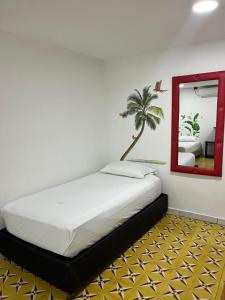 a bedroom with a bed with a mirror and a palm tree at Hotel La Terrazza in Ríohacha