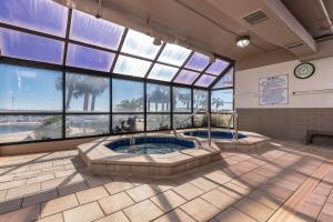 a large room with two hot tubs in a building with windows at Phoenix East 808 in Orange Beach
