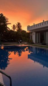 a sunset over a swimming pool in front of a house at Lisbon Lagoons in Negombo