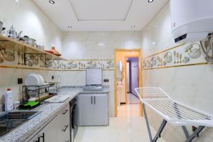 a large kitchen with white counters and a sink at Riad Bollywood-Royal Stay C in Benguerir