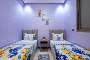 two beds in a room with purple walls at Riad Bollywood-Royal Stay C in Benguerir