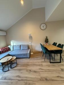 a living room with a couch and a table and a clock at Belle View Strumyk 212 - Mountain View & SPA in Szklarska Poręba