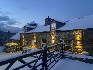 a stone house with christmas lights on it in the snow at Garth Engan B&B with private lounge in Llanbedr