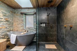 a bathroom with a tub and a glass shower at Stone Cottage in Arrowtown +9 photos
