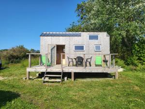 a tiny house on a dock with chairs on it at maison du bonheur in Tréflez