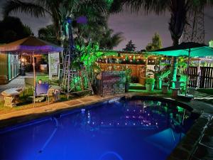 a swimming pool with lights in a backyard at night at Bosveld In Die Stad Lodge in Alberton