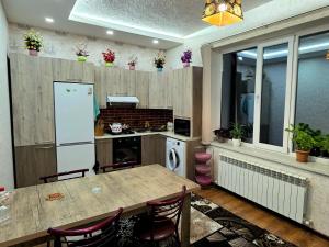 a kitchen with a table and a white refrigerator at Dom Semya Gusar in Qusar