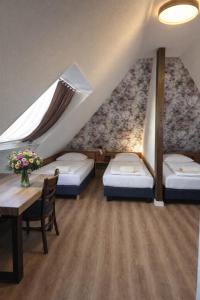 ein Zimmer mit drei Betten und einem Tisch mit Blumen in der Unterkunft Hotel Pirol in Berlin