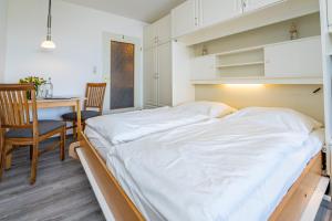 a bed in a room with a table and chairs at Wiking, App 201A in Westerland