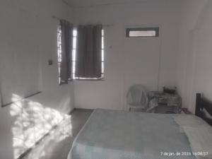 a bedroom with a bed and a chair and a window at Nelson Pinheiro in São Luís