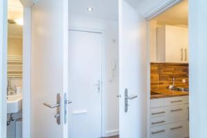 a kitchen with white cabinets and a sliding door at Sylter Residenz, App 56 in Westerland