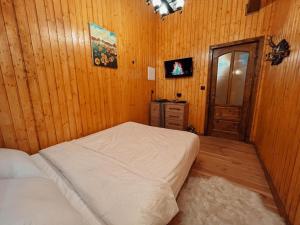 a bedroom with a bed and a wooden wall at Casuta Cerbului Colibita in Colibiţa