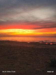 a sunset on the beach with the ocean in the background at על הים in Nahariyya +4 photos