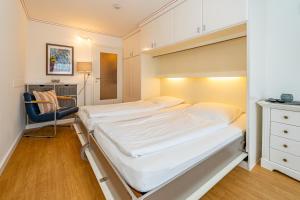a bedroom with two beds and a chair at Wiking, App 003 in Westerland