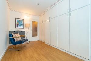 a living room with white cabinets and a blue chair at Wiking, App 003 in Westerland