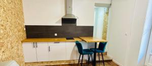 a kitchen with white cabinets and two blue chairs at Studio in Aurillac